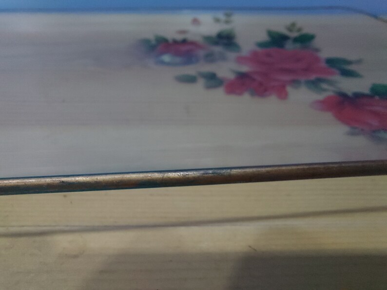 Pode incluir: Um prato de vidro para assar com um design floral com rosas cor-de-rosa e folhas verdes. O prato tem uma borda castanha.