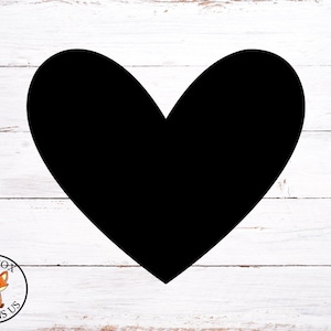 Puede incluir: Una forma de corazón negra sobre un fondo de madera blanca.
