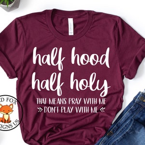 May include: A maroon t-shirt with white text that reads "half hood half holy that means pray with me >> don't play with me <<"