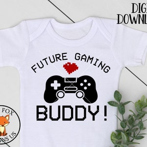 Può includere: Body bianco per neonato con testo pixelato nero e rosso che dice "Future Gaming Buddy!" con un cuore pixelato rosso e un controller per videogiochi pixelato nero.