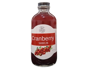 May include: A clear glass bottle filled with deep red cranberry shrub liquid. The white label features the text "Cranberry SHRUB" in red and white, a graphic of red cranberries, and the text "8 fl oz." at the bottom right corner.