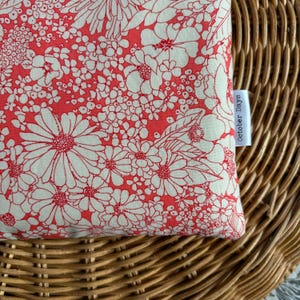 May include: A red fabric pouch with a white floral pattern. The pouch has a white tag attached to it that says "October Days".