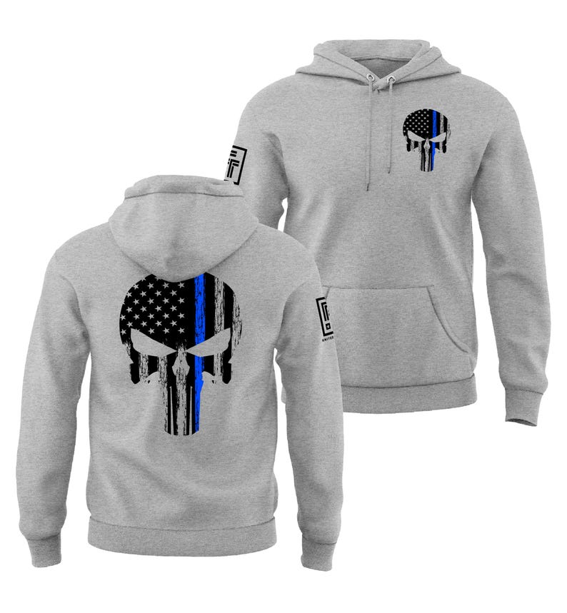 May include: Two gray hooded sweatshirts with a skull design. The skull is a combination of the American flag and a blue line. One sweatshirt has the design on the back, and the other has it on the front. Both sweatshirts have a front pocket and a hood.
