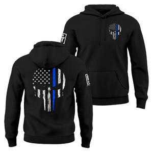 May include: Black hoodie featuring a skull design with the American flag and a blue line. The design is on the front and back of the hoodie. The hoodie has a hood and a front pocket.