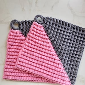May include: Two crocheted pot holders, one pink and one grey, with a diagonal split between the colours. Each pot holder has a loop handle.