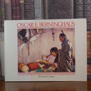 May include: Book cover featuring a painting of Native Americans in a landscape setting. The title of the book is "Oscar E. Berninghaus, Master Painter of American Indians and the Frontier West" by Gordon E. Sanders.
