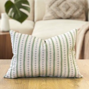 May include: A green and white striped cushion with a subtle leaf pattern. The cushion is made of a soft, textured fabric and has a simple, elegant design.