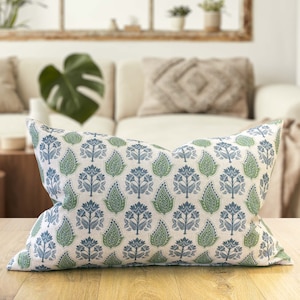 Könnte beinhalten: Ein dekoratives Kissen mit weißem Hintergrund und einem sich wiederholenden Muster aus blauen und grünen Blumenmotiven.