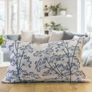 Op de afbeelding: Een decoratief kussen met een beige achtergrond en een blauw bloemenpatroon. Het kussen is gemaakt van een zachte, textuurrijke stof en heeft een subtiel, elegant ontwerp.