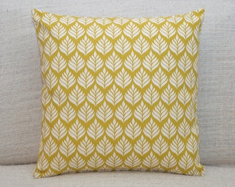 Almofada minimalista escandinava com estampa de folhas. Dupla face, quadrada, 43x43 cm. 100% algodão. Amarelo mostarda ocre. Design floral botânico escandinavo.
