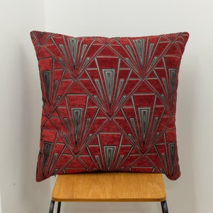 Può includere: Cuscino decorativo rosso e nero con un motivo geometrico a forma di ventaglio.