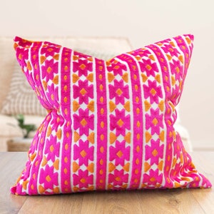 Peut inclure: Un coussin de décoration rose et orange avec un motif géométrique. Le coussin est fait d'un tissu doux et moelleux.