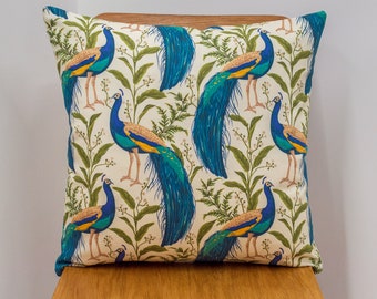 Vibrante cojín estampado de pavo real en crema y azul verde azulado. 17x17" Doble cara. 100% Algodón. Diseño vintage de hojas y pájaros botánicos.