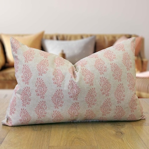 Può includere: Un cuscino lombare rosa e bianco con un motivo floreale. Il cuscino è realizzato in un tessuto morbido e naturale.