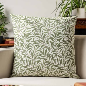 Puede incluir: Una almohada de tiro verde y blanca con un diseño de hojas. La almohada está hecha de una tela suave y tejida y tiene una forma cuadrada.