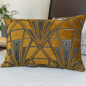 Könnte beinhalten: Ein goldfarbenes und schwarzes Kissen mit geometrischem Muster. Das Kissen ist rechteckig und hat eine weiche, plüschige Textur.