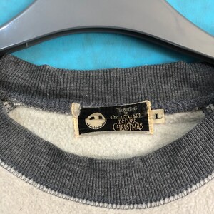 K&ouml;nnte beinhalten: Ein wei&szlig;-graues Sweatshirt mit einem schwarz-wei&szlig;en Etikett, auf dem "Tim Burton's The Nightmare Before Christmas" steht. Das Etikett zeigt eine schwarz-wei&szlig;e Illustration von Jack Skellingtons Gesicht.