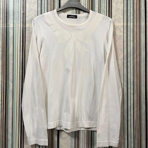 May include: White long-sleeve shirt with a large bow detail on the chest. The shirt is hanging on a black hanger. The shirt has a crew neck and is made of a soft material. The shirt is a solid white color.