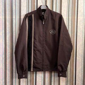 May include: A brown jacket with a zipper closure and a white and black stripe down the left side. The jacket has a logo on the left chest that says "COOGI".