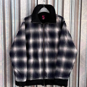 May include: A black and white plaid jacket with a black knit collar and cuffs. The jacket has a zipper closure and a small tag on the collar.