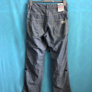 May include: Blue denim trousers with a green and white label that says "Elusion Uncomfortable Clothing".