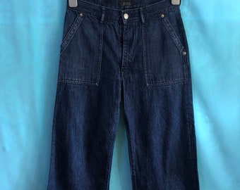 May include: Dark blue denim wide-leg cropped pants with a button fly and two large patch pockets on the front.