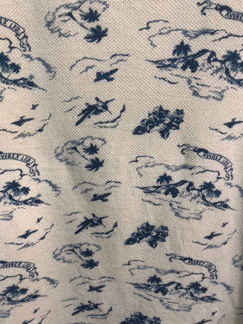 May include: A white fabric with a blue pattern of palm trees, airplanes, and clouds. The fabric has the text "AVIREX LTD" repeated throughout the pattern.