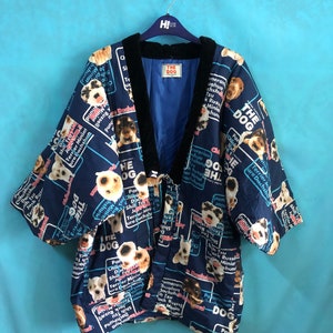 May include: A blue and black short-sleeved kimono with a dog print. The kimono has a black velvet collar and a label that says "The Dog". The print features various dog breeds and the words "The Dog" repeated throughout.