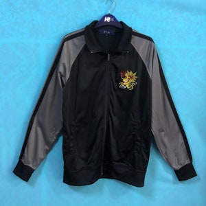 May include: Black and gray zippered jacket with a gray and black striped design on the sleeves. The jacket has a gold embroidered dragon on the front with the text "X11k".
