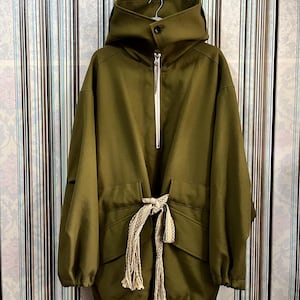 May include: A green hooded jacket with a drawstring waist and a zipper closure. The jacket has a relaxed fit and is made of a soft, comfortable fabric.