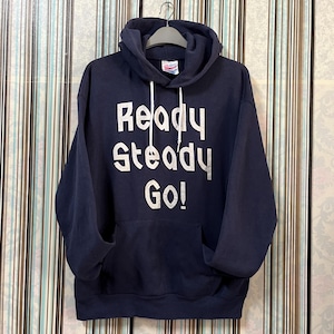 May include: Navy blue hooded sweatshirt with the words "Ready Steady Go!" printed in white block letters. The sweatshirt has a drawstring hood and a front pocket. The garment is hanging on a gray hanger.