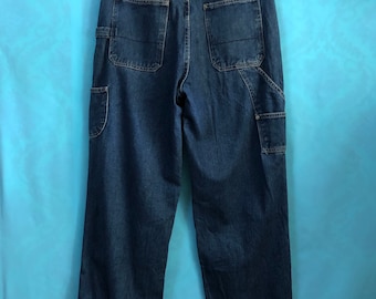 May include: Dark blue denim carpenter jeans with a brown leather patch that says "Nautica" on the back right pocket.