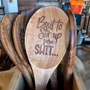 Puede incluir: Un juego de cucharas de madera con un dicho divertido grabado en una de las cucharas: "Bout to Stir Up Some SH!T..."
