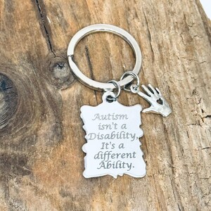 May include: Silver keychain with a hand charm and a tag that reads "Autism isn't a Disability. It's a different Ability."