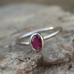 May include: A silver ring with a red oval gemstone.