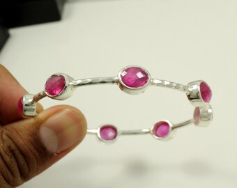 Puede incluir: Un brazalete de plata con seis piedras preciosas rosas. El brazalete tiene una textura martillada.