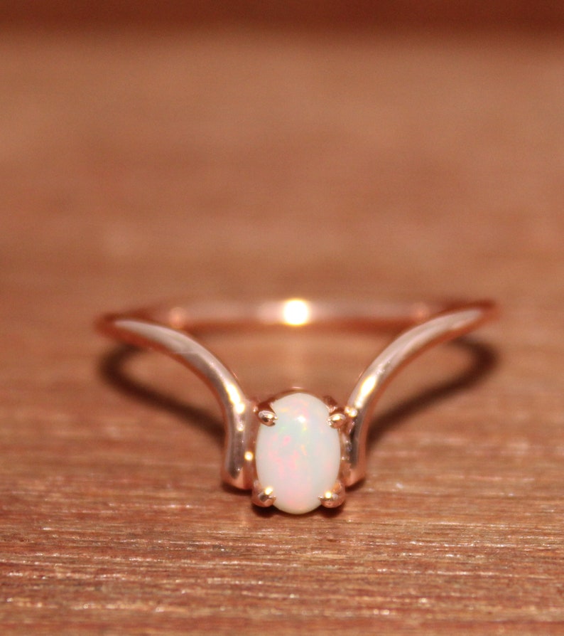 May include: A delicate rose gold ring with a white opal gemstone set in a simple, elegant design.