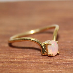 May include: A gold ring with a white opal gemstone. The ring has a simple, delicate design.