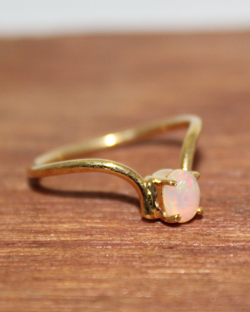 May include: A gold ring with a white opal gemstone. The ring has a simple, delicate design.