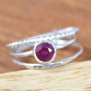 Peut inclure: Une bague en argent compos&eacute;e de trois anneaux, l'anneau sup&eacute;rieur pr&eacute;sente un motif de corde torsad&eacute;e, l'anneau du milieu est uni et l'anneau inf&eacute;rieur est martel&eacute;. Un seul rubis rond est serti au centre de la bague.