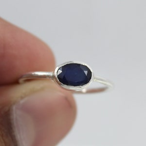 May include: A silver ring with a dark blue oval gemstone.