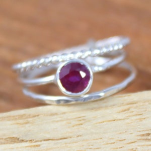 Peut inclure: Une bague en argent compos&eacute;e de trois anneaux, l'anneau sup&eacute;rieur pr&eacute;sente une petite pierre de rubis ronde de couleur rouge fonc&eacute;.
