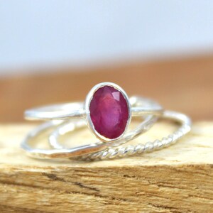 Puede incluir: Un conjunto de anillos de plata, uno con una gran gema de rub&iacute; ovalada. El rub&iacute; es de color rojo intenso y est&aacute; engastado en un bisel de plata. Los otros anillos tienen dise&ntilde;os texturizados y retorcidos.