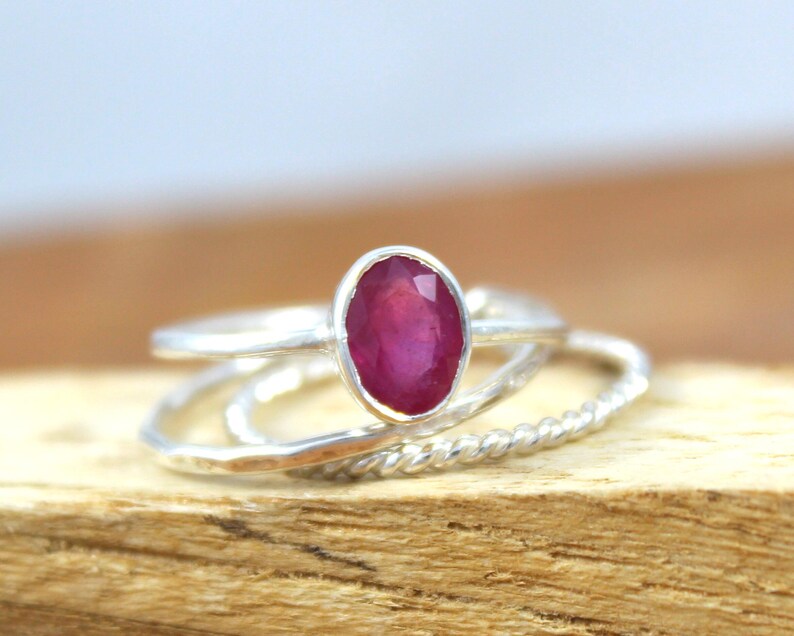 Puede incluir: Un conjunto de anillos de plata, uno con una gran gema de rub&iacute; ovalada. El rub&iacute; es de color rojo intenso y est&aacute; engastado en un bisel de plata. Los otros anillos tienen dise&ntilde;os texturizados y retorcidos.