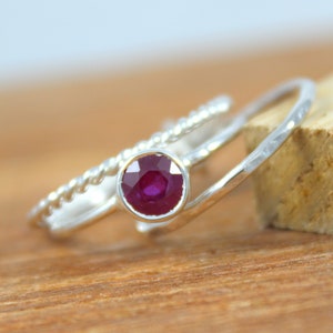 Peut inclure: Une bague en argent sertie d'un rubis rond. La bague est de conception d&eacute;licate avec une bande torsad&eacute;e et une bande martel&eacute;e.