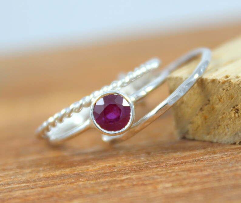 Peut inclure: Une bague en argent sertie d'un rubis rond. La bague est de conception d&eacute;licate avec une bande torsad&eacute;e et une bande martel&eacute;e.