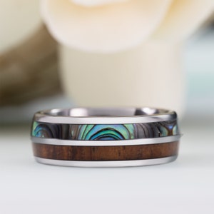 May include: A silver ring with a brown wood inlay and a blue and green abalone shell inlay.