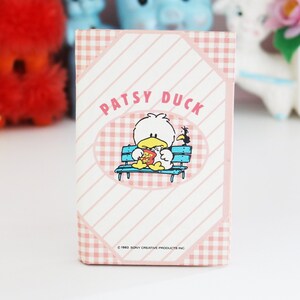 May include: A vintage Patsy Duck greeting card with a cartoon duck on a bench, eating. The card has a pink and white gingham and striped design. The text "Patsy Duck" is at the top.