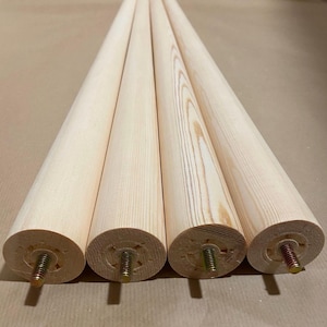 May include: Four unfinished wooden legs with threaded metal inserts. The legs are approximately 30 cm long and 3.8 cm in diameter.