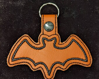 May include: Orange leather bat keychain with black stitching and a silver metal ring.